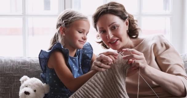 Happy mature grandma teach preschool granddaughter learn knitting needles together — Stockvideo