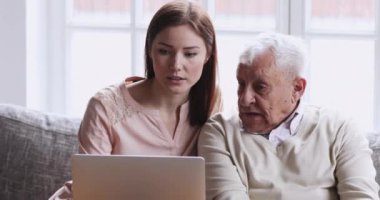 Genç torun, büyük babaya dizüstü bilgisayar kullanarak öğrenme öğretiyor.