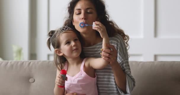 Happy young nanny blowing soap bubbles with kid girl. — Stockvideo