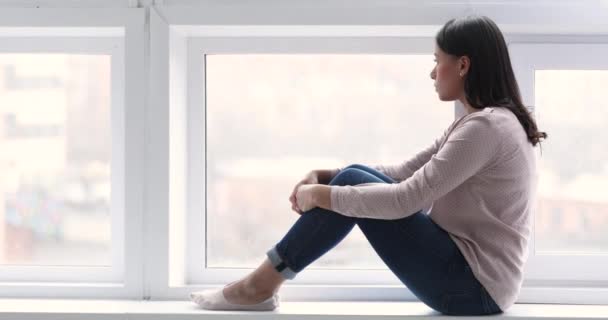 Femme afro-américaine réfléchie assis sur le seuil regardant par la fenêtre — Video