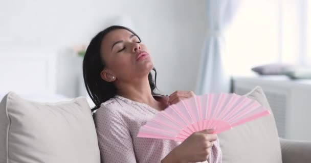 Young african woman waving fan suffer from heat at home — Stock video