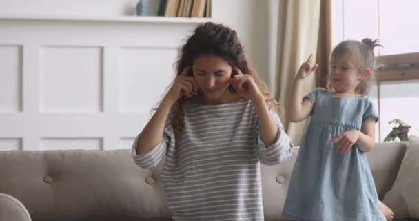 Frustrated young nanny babysitter plugging ears, ignoring loud kid girl. — Stockvideo