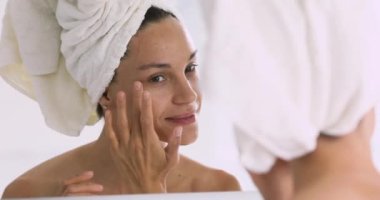 Mutlu genç melez kadın aynaya bakıyor, tenine dokunuyor..