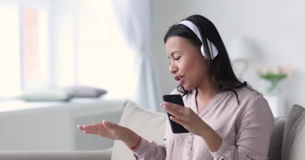 Беззаботная молодая женщина смешанной расы наслаждается новой крутой мобильной музыкой — стоковое видео