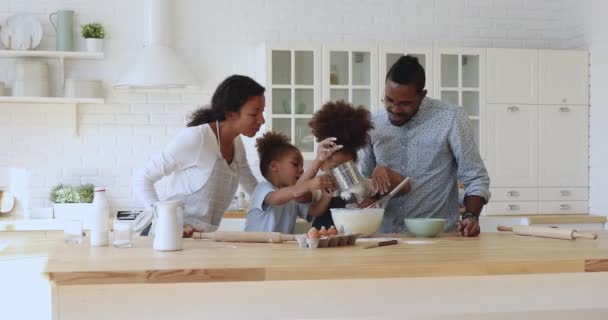 Gelukkige Afrikaanse etniciteit ouders kijken kinderen broers en zussen koken. — Stockvideo