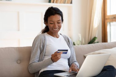 Happy biracial woman shopping online using laptop
