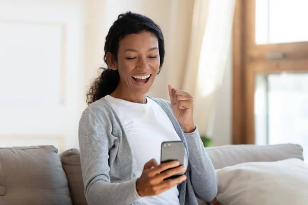 Overjoyed biracial woman read good news on cellphone — Stockfoto