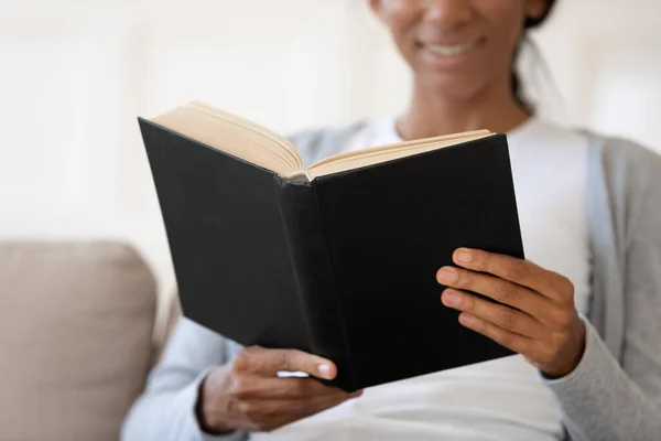 African American woman reading book relaxing at home — ストック写真