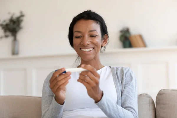 Happy biracial woman look at positive pregnancy test result — Stockfoto