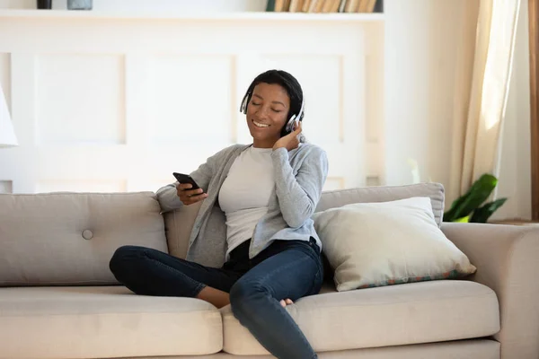 Mujer afroamericana en auriculares con dispositivo de teléfono inteligente — Foto de Stock