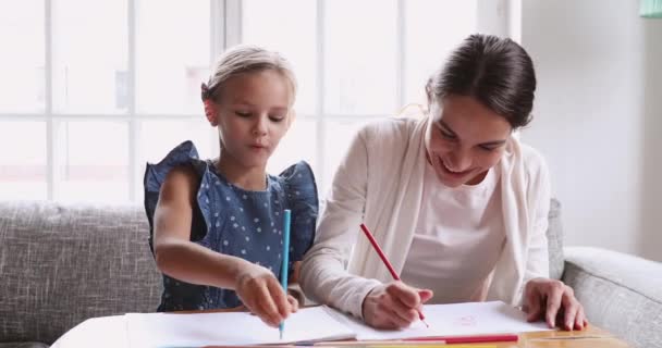 Молодая няня учит школьницу рисовать карандаши вместе — стоковое видео