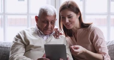 Büyümüş torun, büyükbabaya dijital tablet kullanmayı öğretiyor.