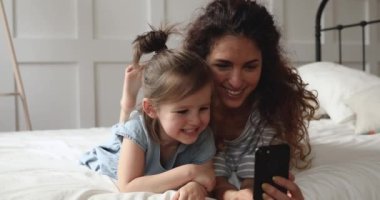 Anneciğin tatlı kızıyla yatakta uzanıyor, özçekim fotoğrafları çekiyor..