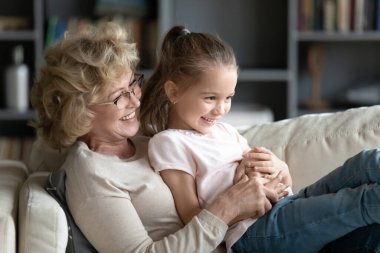 Happy senior grandparent playing with preschooler granddaughter