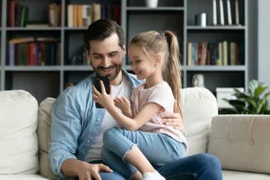 Cute little girl rest with dad using smartphone together