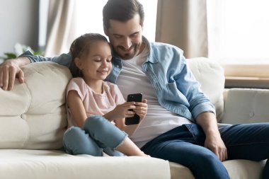 Young father relax with little daughter using cell