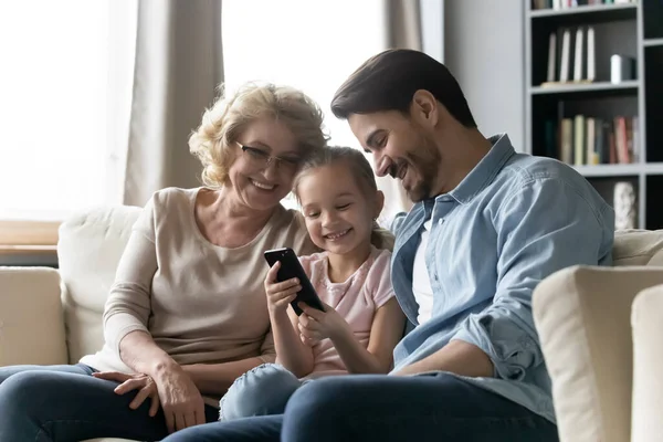 Счастливые три поколения семьи с использованием современных смартфонов — стоковое фото