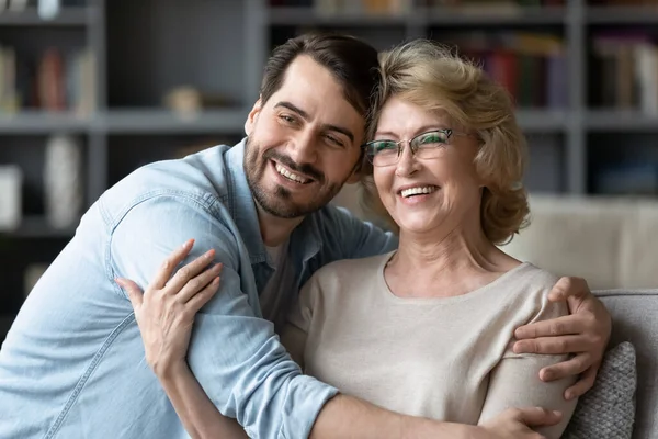 Smiling adult son and senior mother visualize looking in distance — Stockfoto