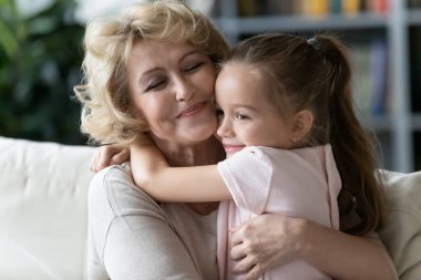 Little girl hug happy 70s grandmother showing love