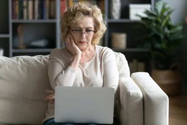 Femme âgée anxieuse lire de mauvaises nouvelles sur ordinateur portable — Photo