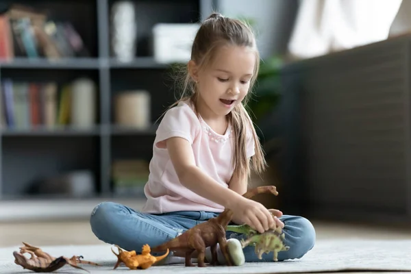 Niña sentada en el suelo jugando con figuras de plástico —  Fotos de Stock