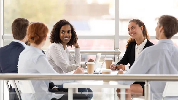 Young smiling diverse women in boardroom at meeting.