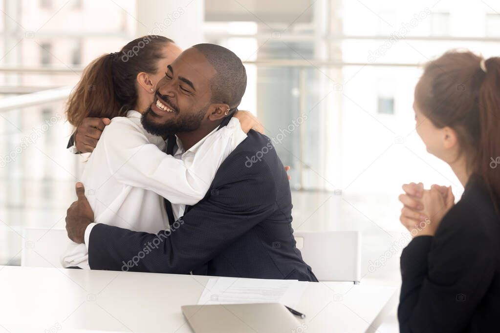 Happy diverse man and woman couple hugging for successful deal