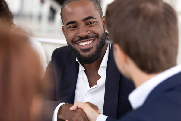Görüşmelerde gülümseyen Afrikalı Amerikalı adam beyaz işadamlarıyla el sıkışıyor.. — Stok fotoğraf