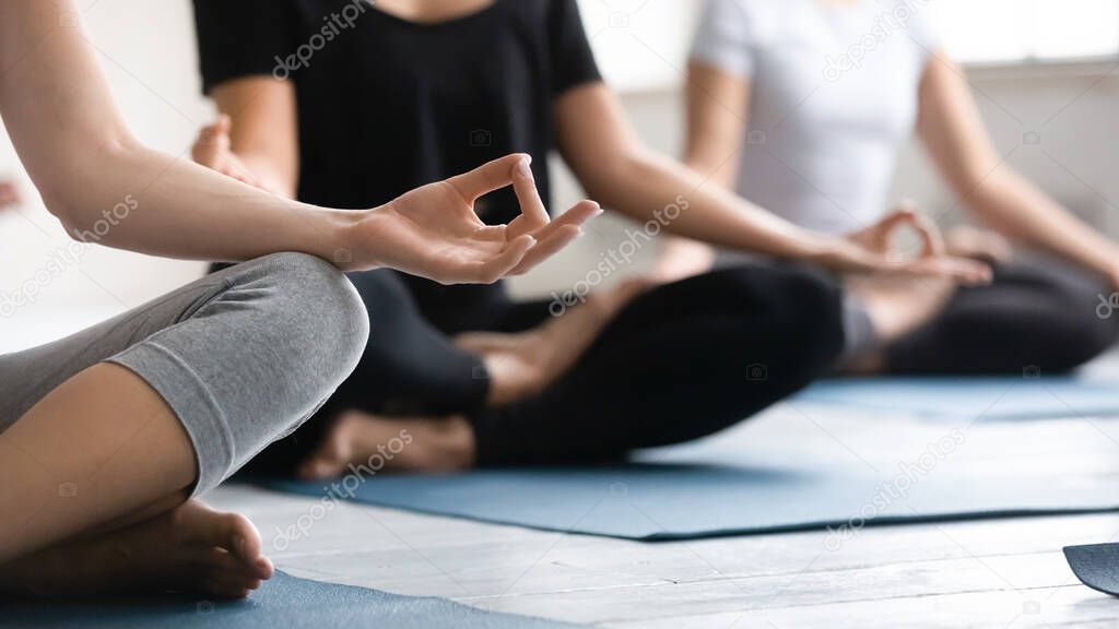 Focus on woman fingers folded in mudra gesture during meditation