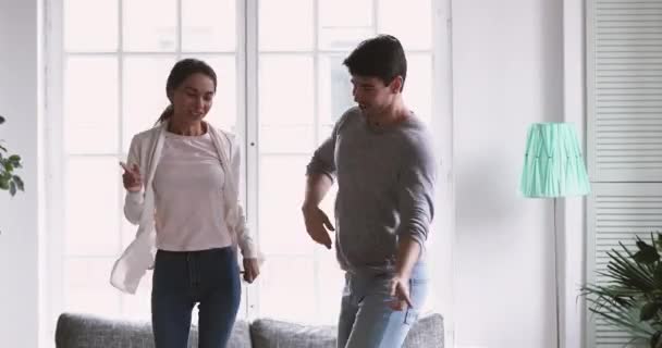 Feliz alegre pareja de jóvenes adultos sin preocupaciones bailando en la sala de estar — Vídeos de Stock