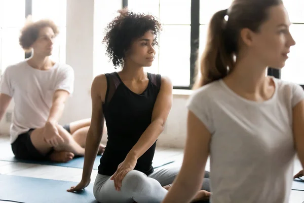 African woman with associates practicing yoga seated in lotus pose — Stock Photo, Image