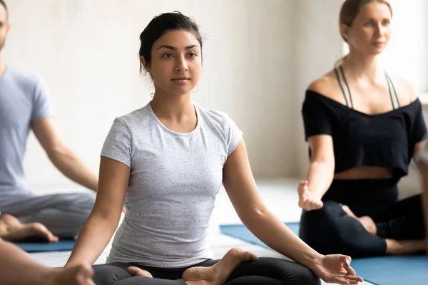 Mujer india con asociados meditando sentados con las piernas cruzadas en las esteras — Foto de Stock