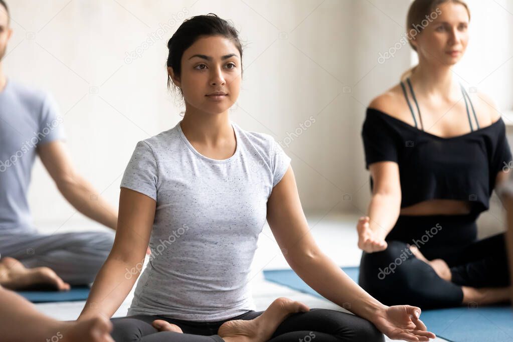 Indian woman with associates meditating seated cross-legged on mats