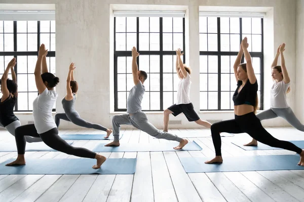 Groupe multi-ethnique de jeunes effectuant Guerrier 1 position de yoga — Photo
