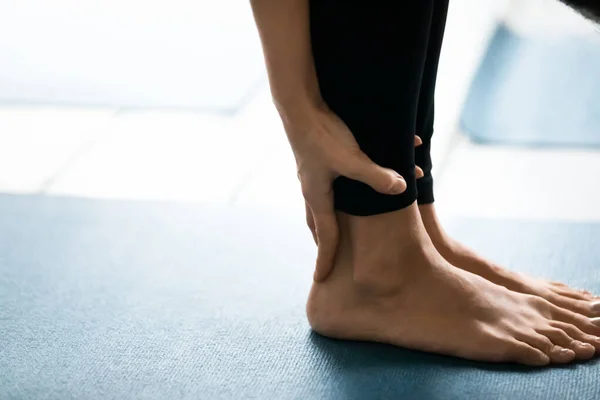 Närbild kvinnliga ben stående barfota på matta utför Uttanasana pose — Stockfoto