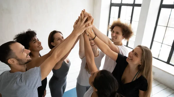 Pessoas multiétnicas felizes em roupas esportivas empilhadas mãos juntas mostrando unidade — Fotografia de Stock