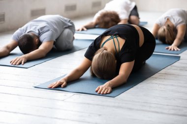 Rahat aktif giyimli insanlar oturum sırasında Balasana gevşeme egzersizi yapıyorlar