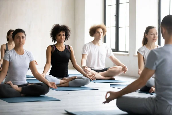 Группа людей, сидящих со скрещенными ногами, занимаются медитацией — стоковое фото