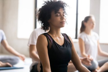 Afrikalı kadın kapalı gözler ortaklarla meditasyon pratiği yapıyor.