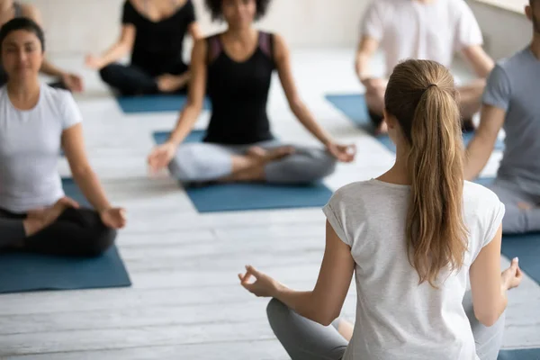 Coach and group of people meditating seated in lotus pose — Stock Photo, Image