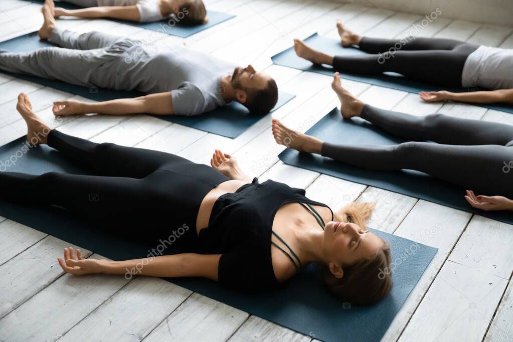 People resting after yoga workout lying in Shavasana Pose