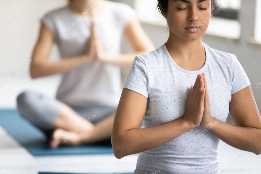 Indian ethnicity woman and associates meditating during yoga class
