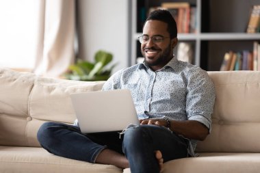 Happy multiracial guy watching movie at home.