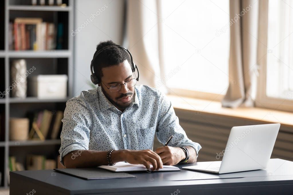 Concentrated biracial guy listening to favorite music while planning workday.