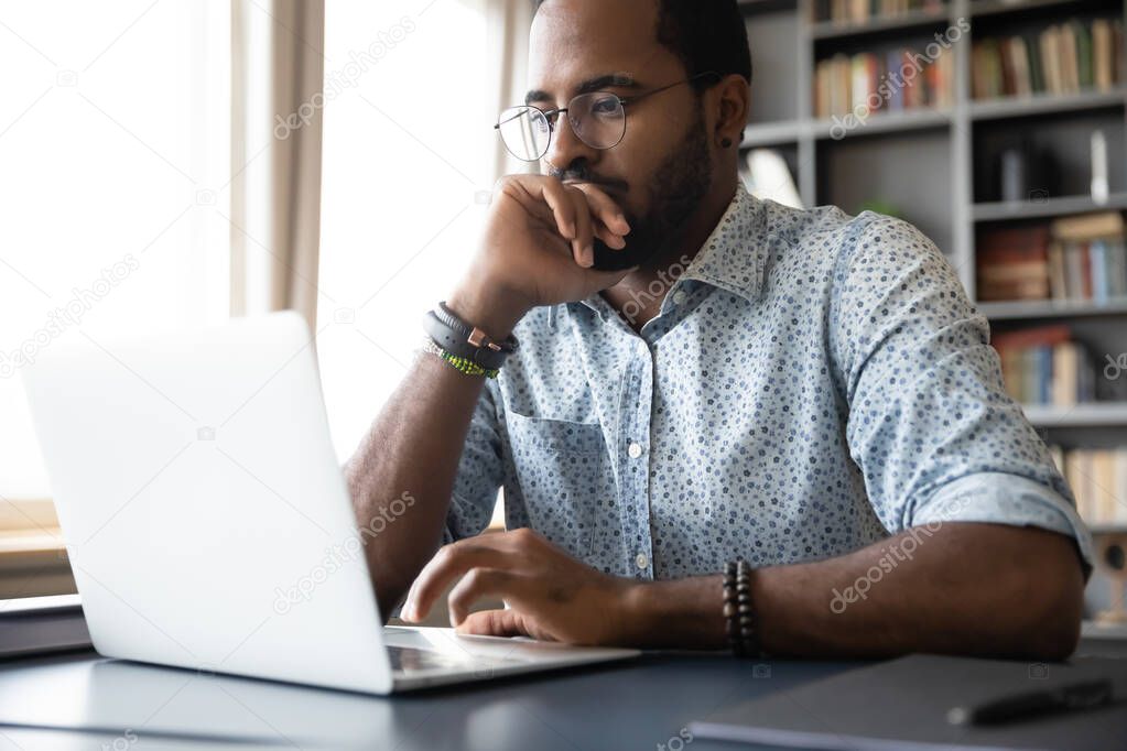 Thoughtful millennial biracial man in eyeglasses stack with hard task.