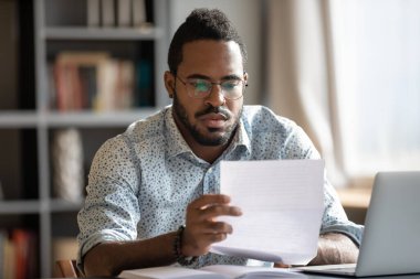 Concentrated biracial businessman analyzing research report.