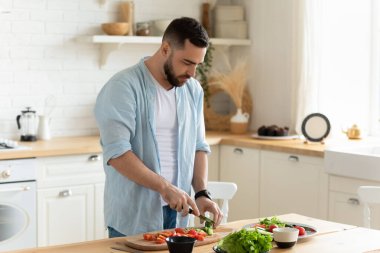 Young man stand in kitchen cooking salad for lunch
