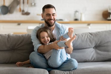 Gülümseyen baba küçük kızıyla oynuyor.