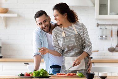 Gülümseyen çift mutfakta birlikte yemek pişiriyor.