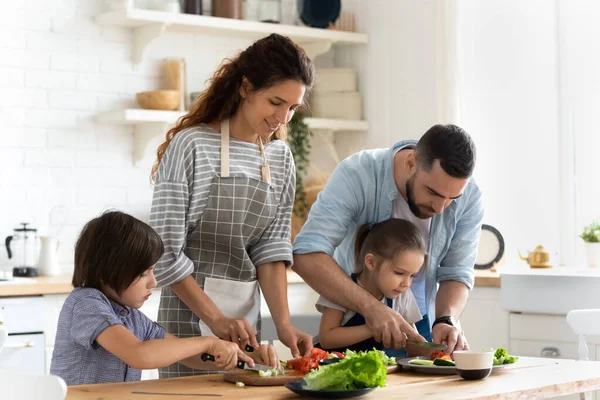 小さな子供が一緒に家で料理をしている若い家族 — ストック写真